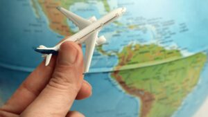 A man moving a toy plane over a world map showing an international trip